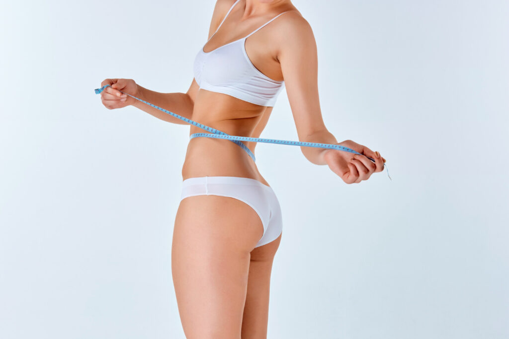 A woman in white underwear holding a blue measuring tape.